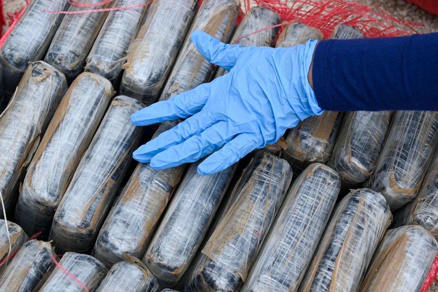 Una mano con guante sobre paquetes que contienen presuntamente cocaína. (Orlando SIERRA / AFP via Getty Images)