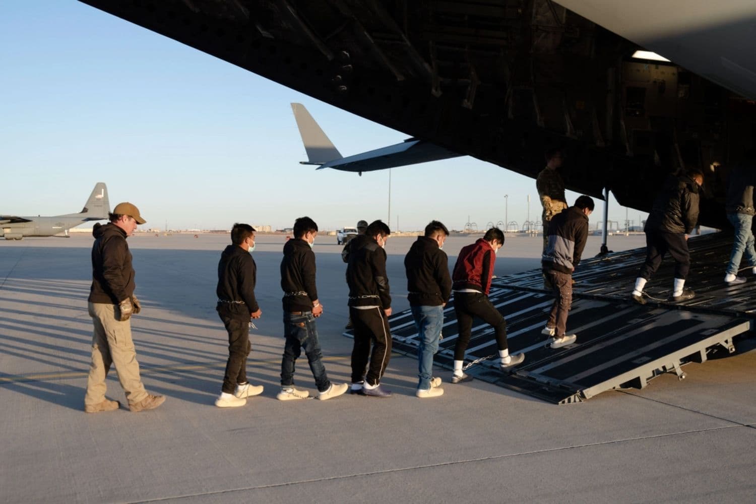 Agentes de seguridad de la Oficina de Aduanas y Protección Fronteriza de EE. UU. guían a inmigrantes ilegales a bordo de un C-17 Globemaster III para un vuelo de deportación en Fort Bliss, Texas, el 23 de enero de 2025. (Foto del Departamento de Defensa tomada por el sargento de primera clase del Ejército de EE. UU. Nicholas De La Peña)
