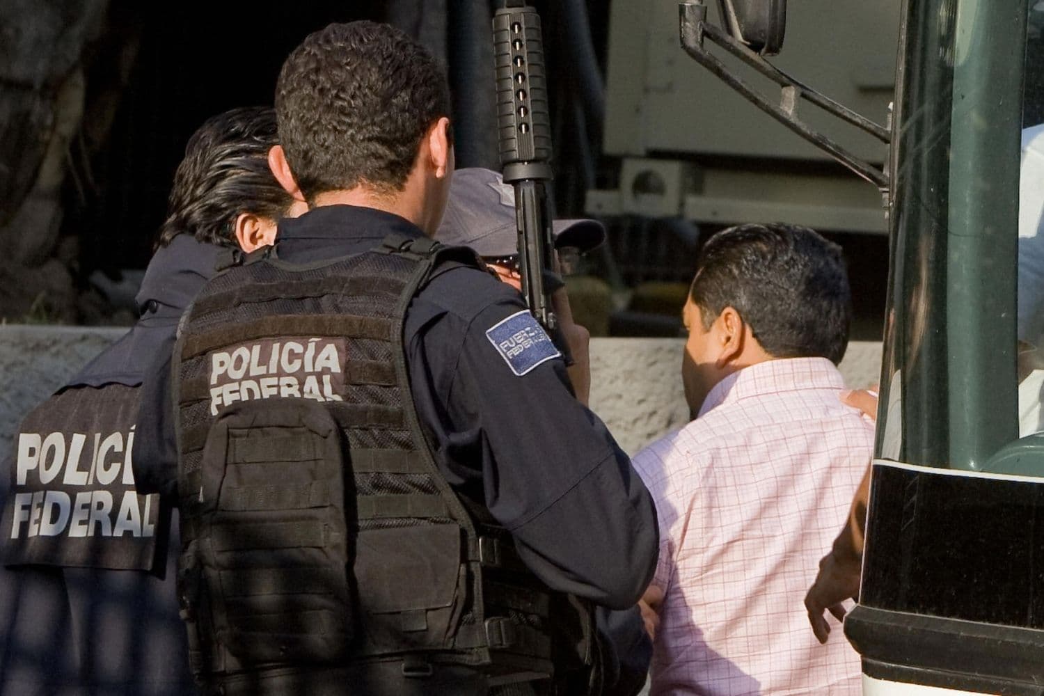 Un agente de la Policía Federal mexicana escolta a un hombre arrestado a su llegada a Ciudad de México, el 26 de mayo de 2009. (ALFREDO ESTRELLA/AFP vía Getty Images)