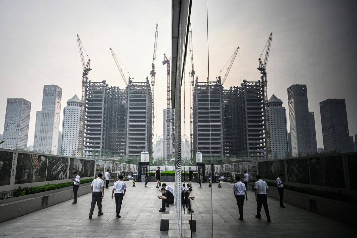Empleados de oficina caminan junto al muro de una obra en construcción en el distrito financiero central de Beijing el 11 de julio de 2024. (Greg Baker/AFP vía Getty Images).
